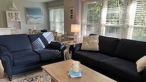 A living room with a dark blue sofa, a light wooden coffee table, and a patterned rug. - Sea Trail 2BR - Golf, Bike, Beach Getaway! Clean, Quiet, Pools, Great View! (Sunset Beach)