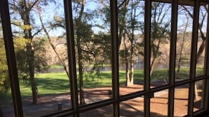 A view through a window with a view of a park with trees and a grassy area. - Sea Trail 2BR - Golf, Bike, Beach Getaway! Clean, Quiet, Pools, Great View! (Sunset Beach)