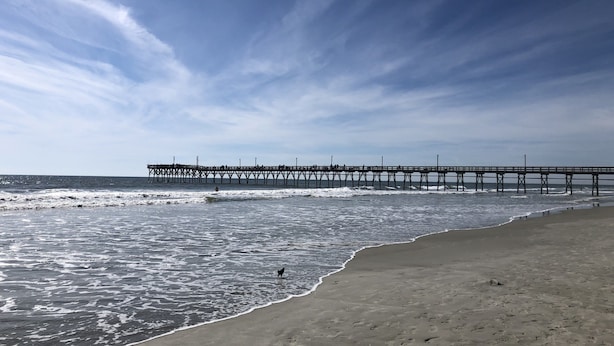 A beach with a pier extending into the ocean, sandy shore, and footprints in the sand. - Sea Trail 2BR - Golf, Bike, Beach Getaway! Clean, Quiet, Pools, Great View! (Sunset Beach)