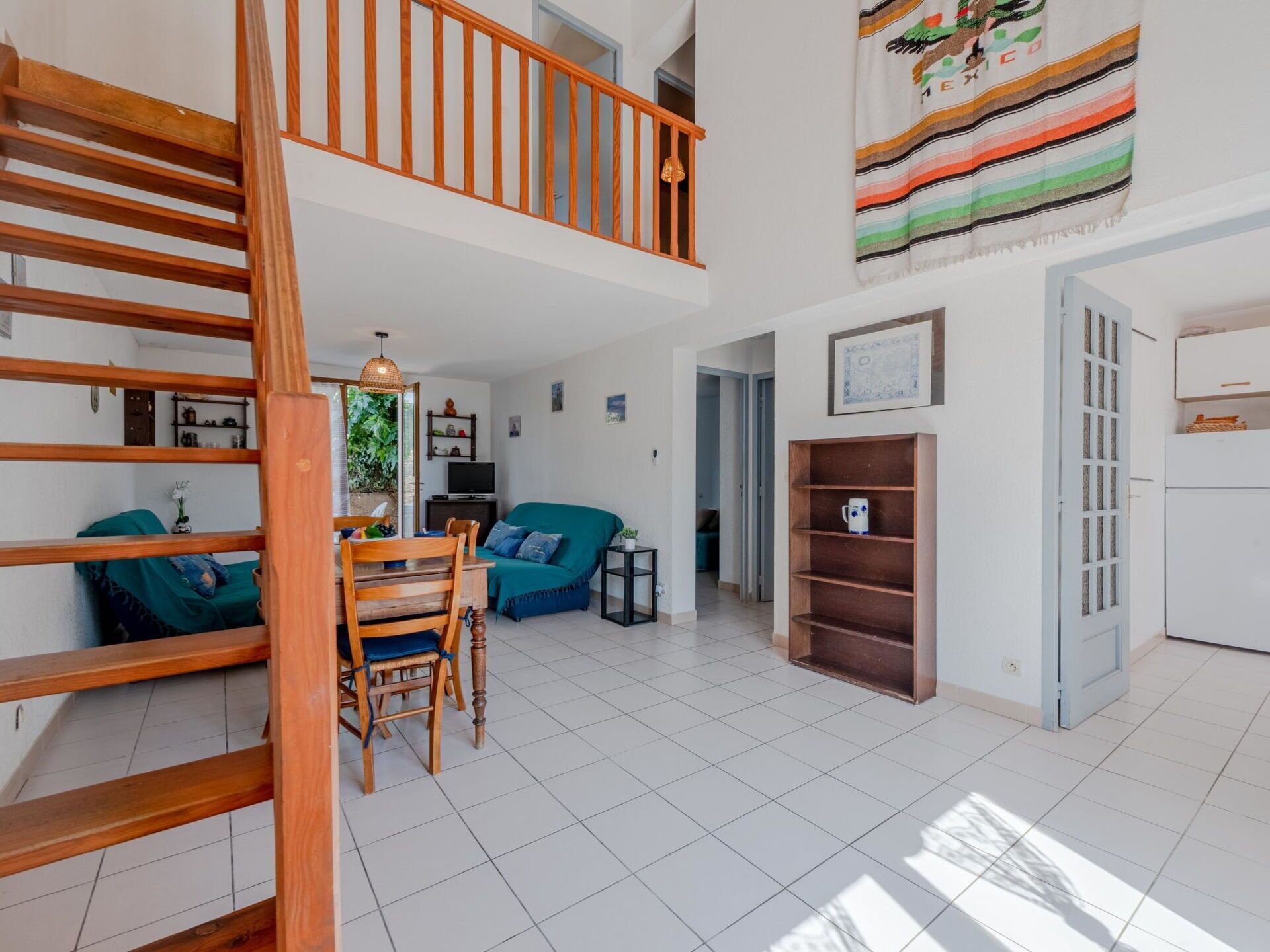 Un vaste espace de vie comprenant un escalier en bois, un ensemble de salle à manger, un canapé et un téléviseur.