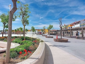 Una plaza pública con árboles, bancos y un parterre circular.