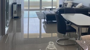 Ein modernes Wohnzimmer mit einem großen Glasfenster, das auf einen Balkon mit Meerblick führt.