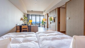 Une chambre d’hôtel avec un grand lit, un bureau avec une chaise, une télévision et une vue sur l’extérieur.