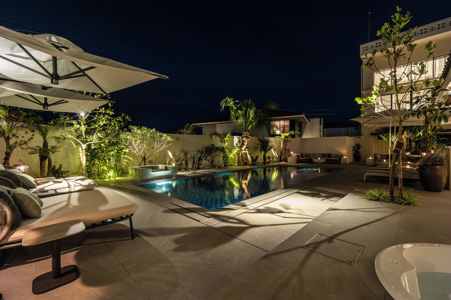 A poolside area with lounge chairs, umbrellas, and a small pool.