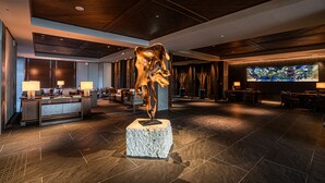Un hall d’entrée agrémenté d’une sculpture centrale, de coins salon et d’un grand tableau abstrait.