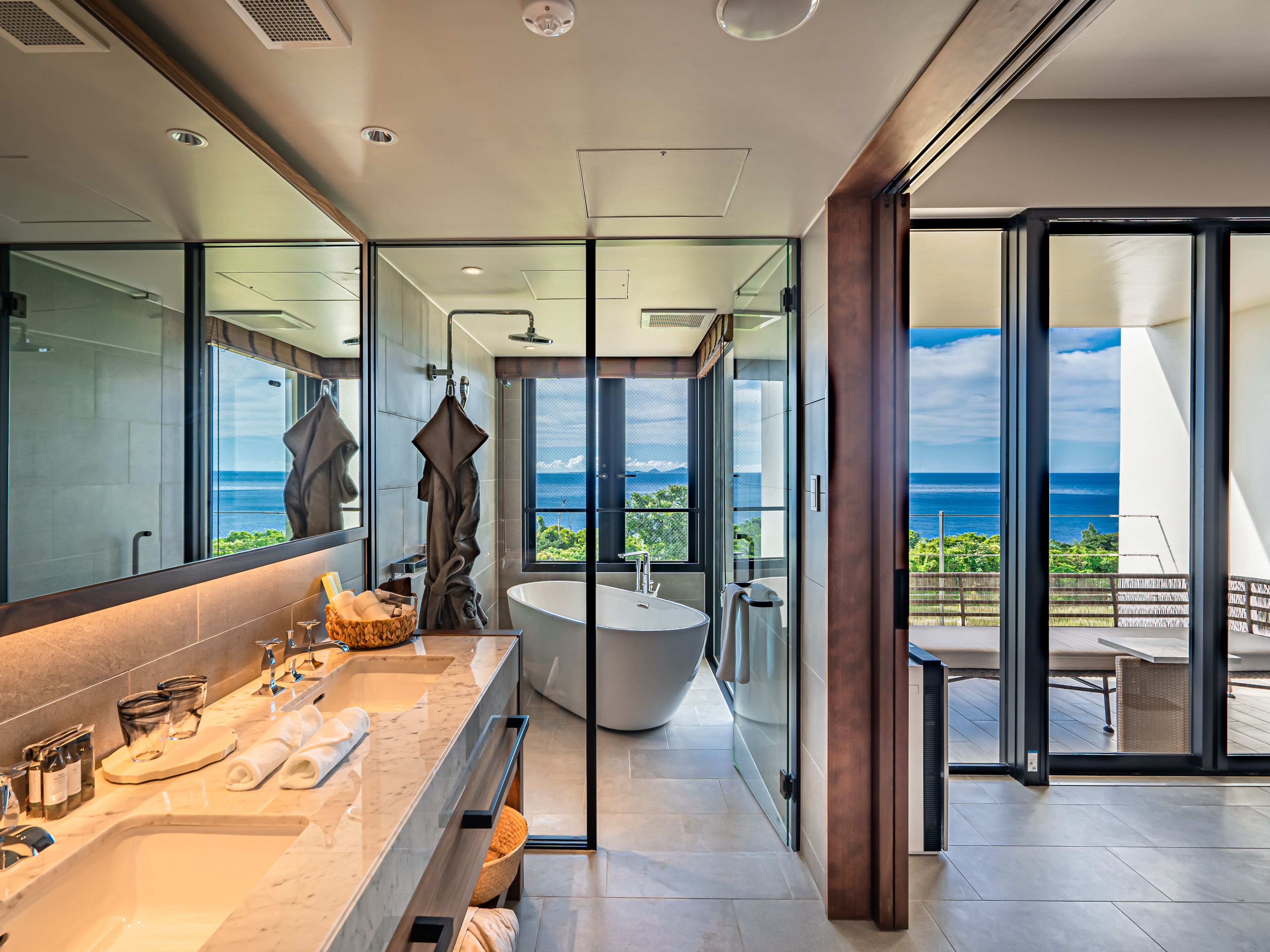 A modern bathroom with a large bathtub, a vanity with a marble countertop, and a large mirror.