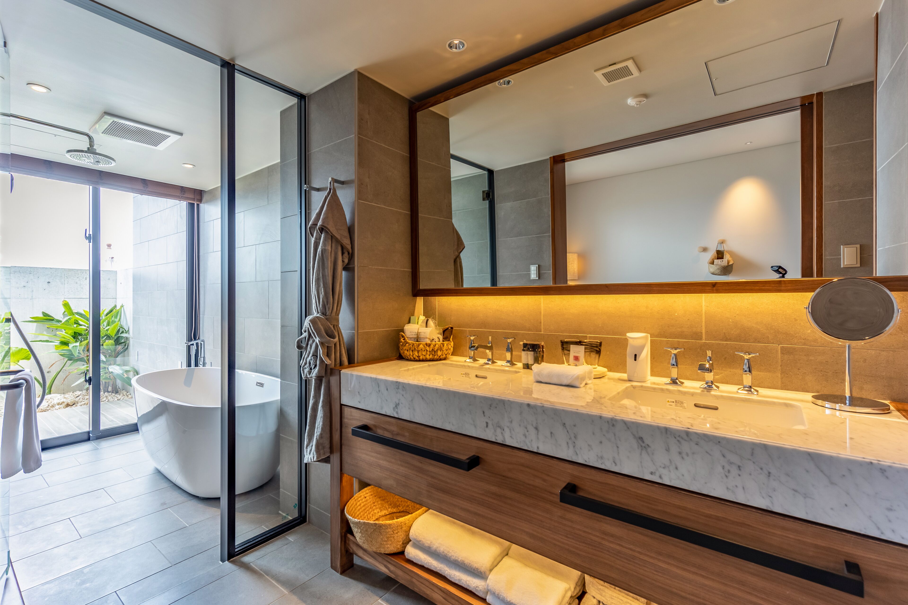 A modern bathroom with a large bathtub, a glass-enclosed shower, and a vanity with a mirror.