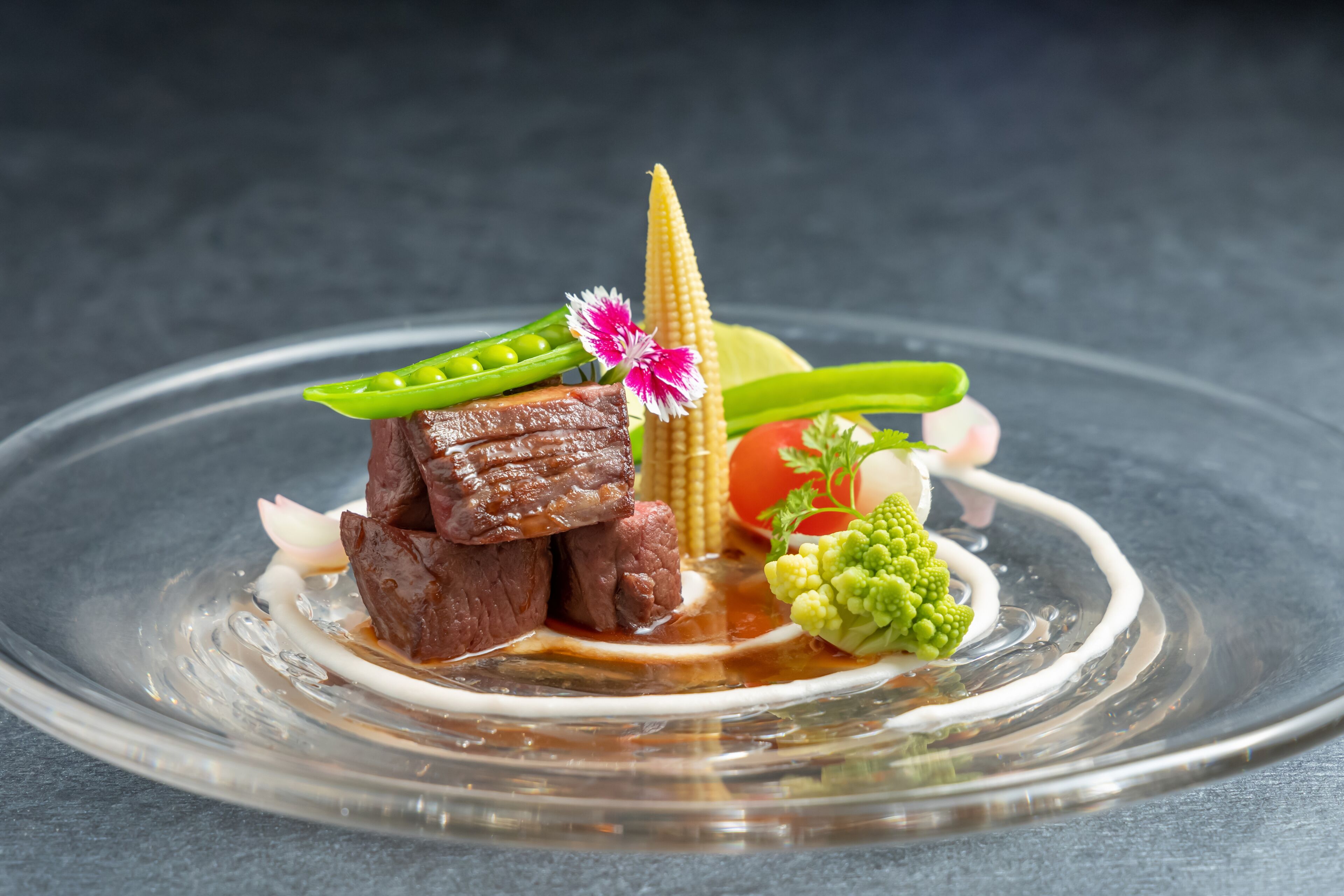 Un plato con carne, verduras y una mazorca de maíz decorativa.