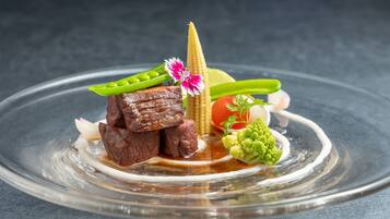 Un plato con carne, verduras y una mazorca de maíz decorativa.