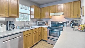 Una cucina moderna con mobili in legno, elettrodomestici in acciaio inossidabile e una finestra che lascia entrare luce naturale.