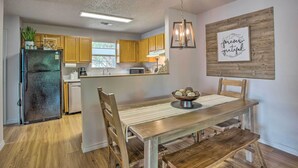 Una cucina moderna con mobili in legno, un frigorifero nero e un'area pranzo con tavolo e sedie in legno.
