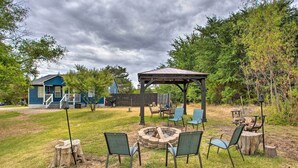 Un giardino sul retro con un focolare, posti a sedere all'aperto, un gazebo e un'area giochi sullo sfondo.