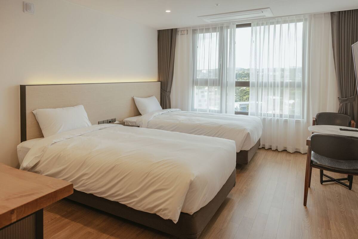 Une chambre d’hôtel avec deux lits, un bureau et une chaise.