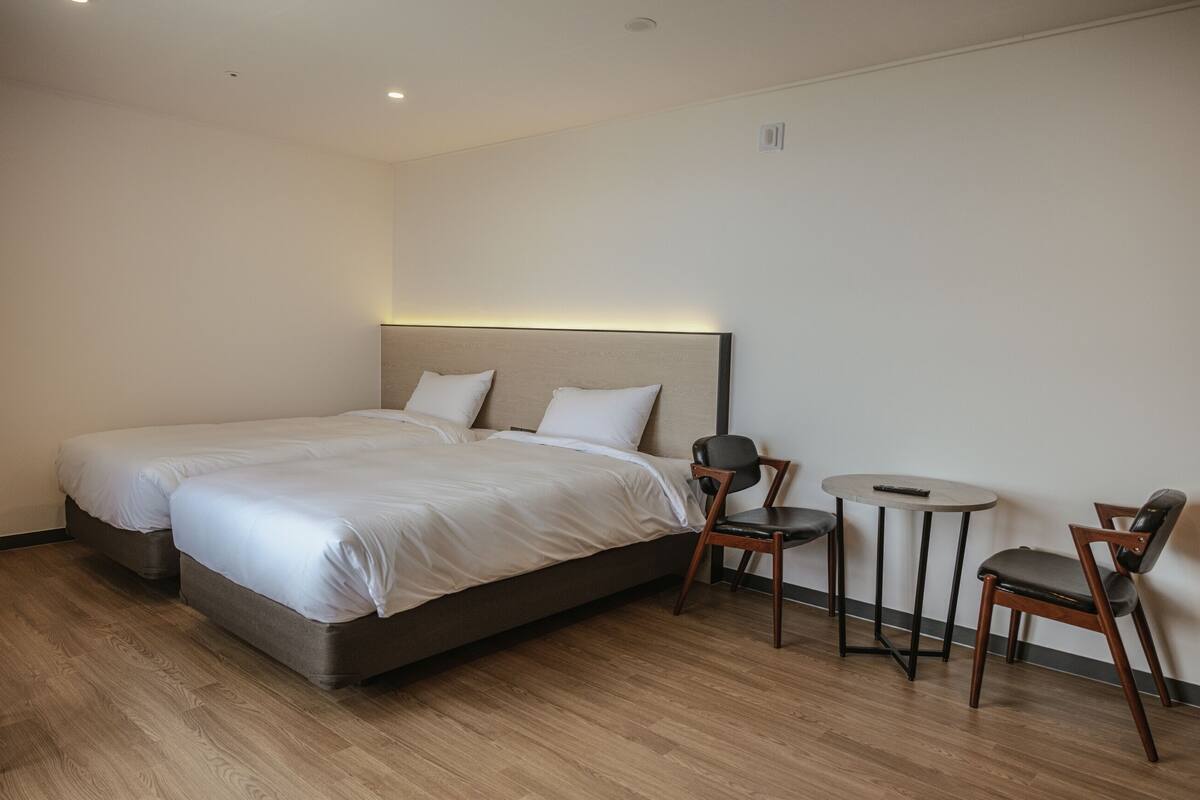 Une chambre d’hôtel avec deux lits, une petite table ronde et deux chaises.