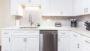 A kitchen with white cabinets, a stainless steel dishwasher, a coffee maker, and a toaster.