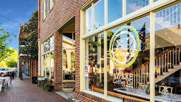 A brick building with a large window displaying a coffee shop sign.