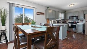 A modern kitchen with grey cabinets, a central island, and a dining area with wooden chairs and a table.