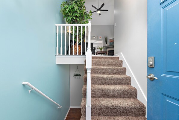 A staircase with a white railing, a blue door, and a ceiling fan. - ⭐️ Luxe Paradise ⭐️ 3 King Beds ✅ Fast Wifi ✅ Free Parking (Raymore)