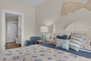 A bedroom with a bed, a nightstand, a lamp, a chair, and a wall-mounted fish sculpture. - Destin West Gulfside 506 ~ Amazing Beach and Pool Views! (Fort Walton Beach)