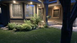 Una casa residencial con un césped cuidado, un amplio ventanal con vistas y un porche con escalones que conducen a la entrada.