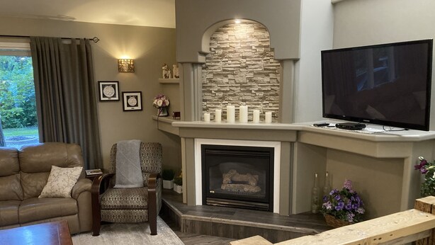 Una sala de estar con chimenea, un sofá, una silla y un televisor.