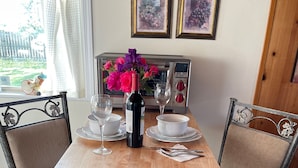Una mesa de comedor con una botella de vino, dos copas de vino y un florero con flores.
