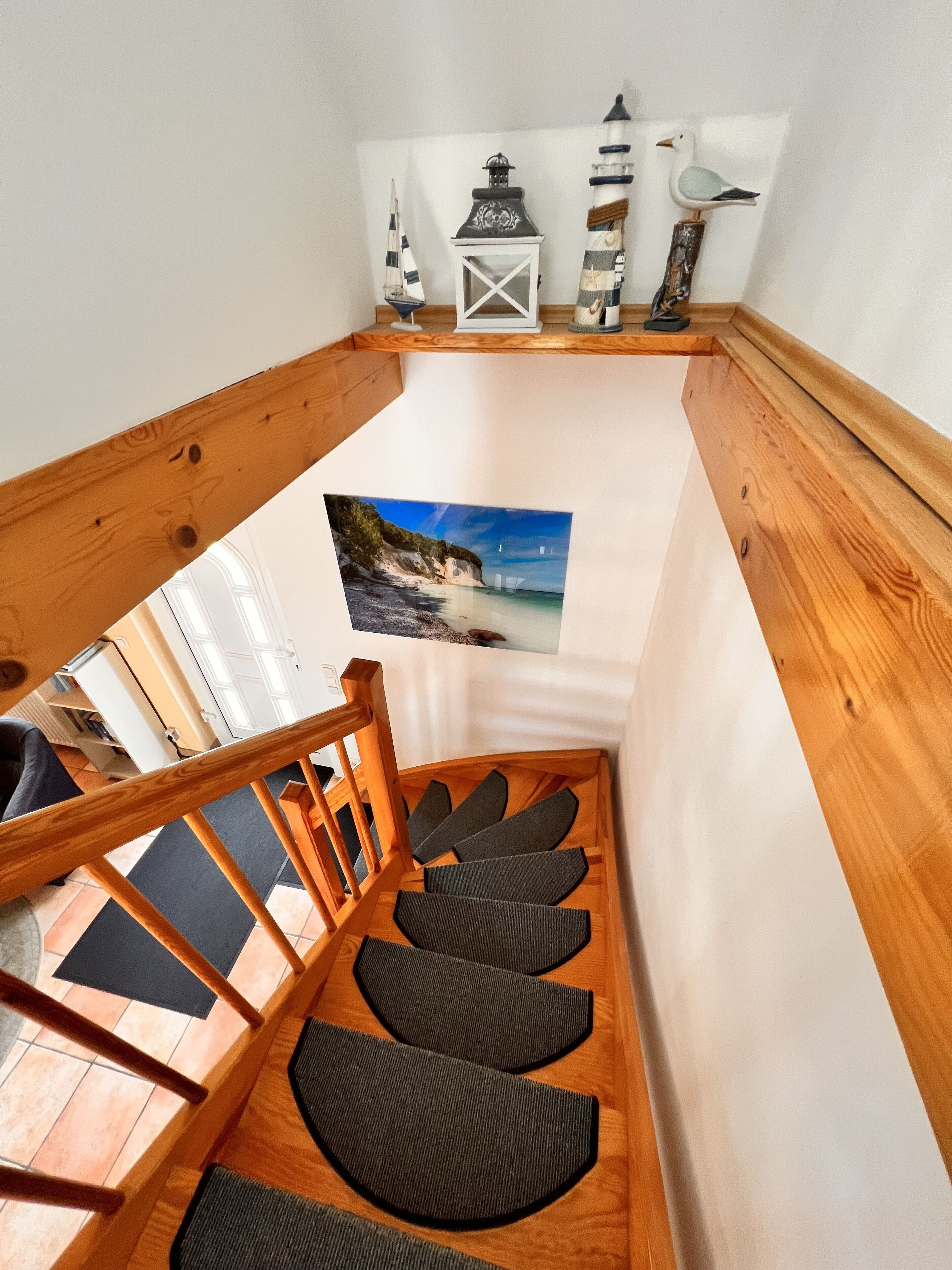 A wooden staircase with a view of a beach through a window.