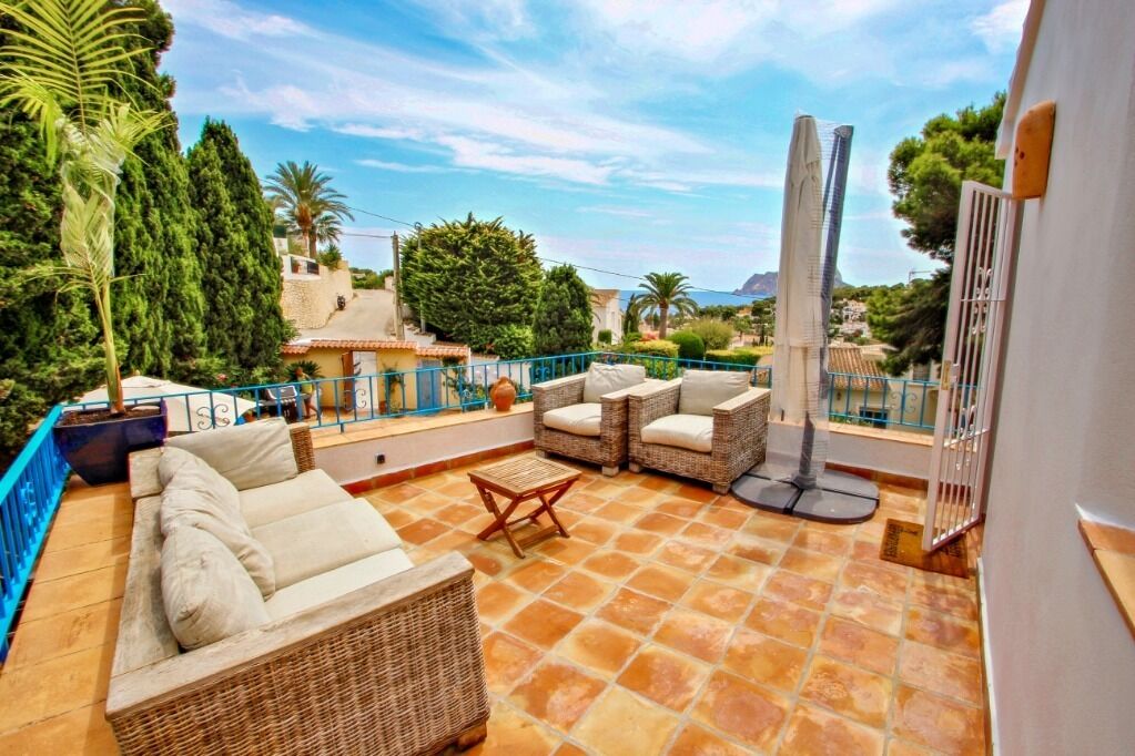 A terrace with wicker furniture, a tiled floor, and a view of the surrounding landscape.