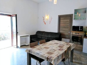 A living room with a sofa, a dining table with a tablecloth, a TV, and a microwave. - APARTMENT 2 BEDROOMS WITH A BEAUTIFUL VIEW - TAIANA (Gravedona Ed Uniti)