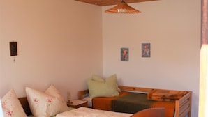 A bedroom with a wooden bed, a nightstand, a hanging lamp, and two wall-mounted pictures. - VACATION AT THE FARM HIDEAWAY IN THE ALPS (Stuhlfelden)