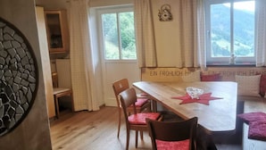 A cozy dining area with a wooden table, red cushioned chairs, and a bench with pillows. A decorative star is on the table, and there's a window with curtains. - VACATION AT THE FARM HIDEAWAY IN THE ALPS (Stuhlfelden)