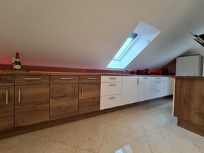 Une cuisine moderne avec des meubles en bois, un puits de lumière et une bande lumineuse à DEL rouge.