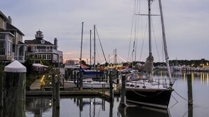 A marina with docked boats, a large house with a balcony, and a calm water body reflecting the sky. - Gorgeous 3 BR, 2.5 BA, 5 Miles to Bethany Beach, Pool, Tennis, Walking Trails, and Free Activities! (Frankford)