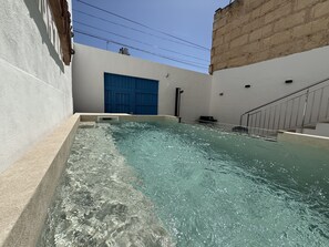 A swimming pool with clear water, a blue door, and a staircase leading up to a building.