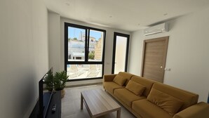 Una sala moderna con un sofá, una mesa de centro y un televisor sobre un mueble.