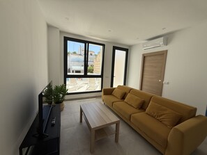 Un soggiorno moderno con un divano, un tavolino da caffè e una TV su un mobile.