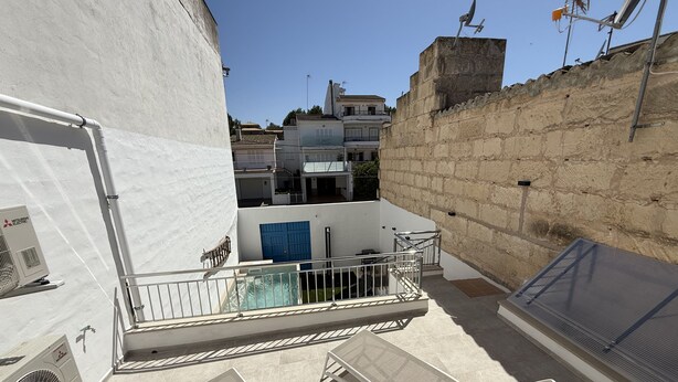 Una terraza en la azotea con piscina, sillas de descanso y vistas de los edificios circundantes.