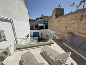 En tagterrasse med swimmingpool, liggestole og udsigt over de omkringliggende bygninger.