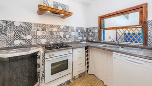 Una cocina con baldosas estampadas, estufa a gas, horno empotrado y una ventana con marco de madera.