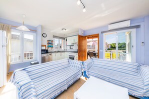 Een kamer met een bed, kitchenette en balkon met uitzicht.