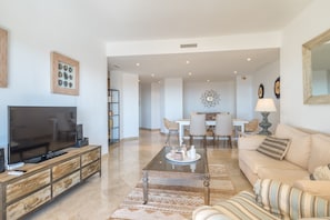 A living room with a TV, sofa, coffee table, and dining area.