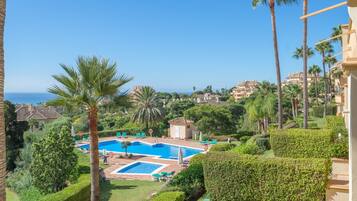 A resort with a swimming pool, palm trees, and a view of the sea.