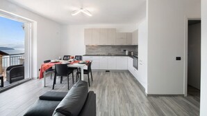 A modern apartment with a balcony, a dining area, and a kitchen. - New Apartment Casa Andrea with Lake View, Terrace and On-Site Free Parking (TREZZONE)