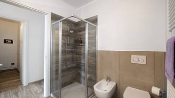 Une salle de bain moderne avec une douche à parois de verre, un bidet et des toilettes.