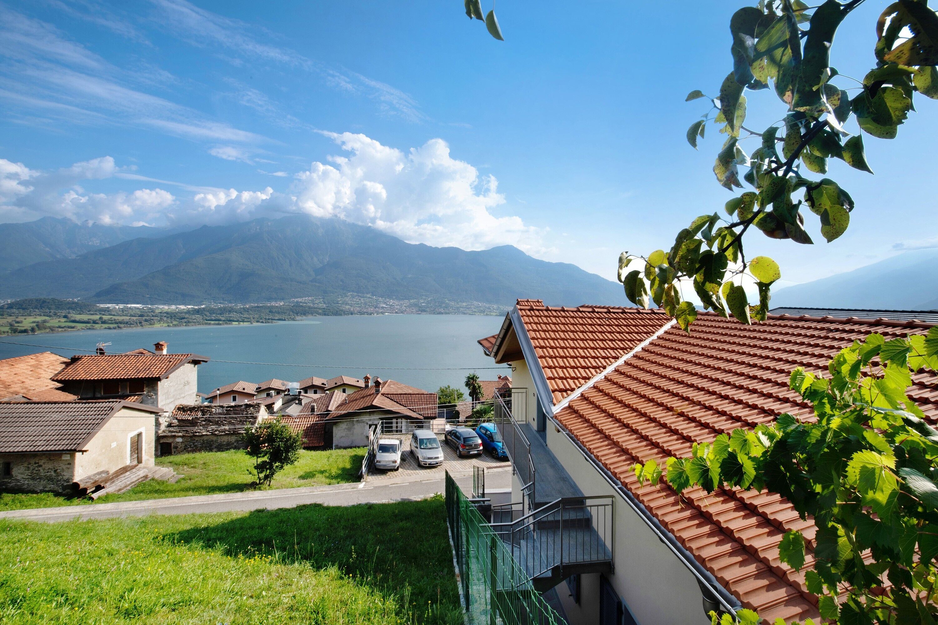 Un barrio residencial con casas, una carretera y un lago con montañas al fondo.