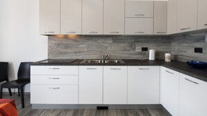 A modern kitchen with white cabinets, a dark countertop, and a built-in sink. - New Apartment Casa Andrea with Lake View, Terrace and On-Site Free Parking (TREZZONE)