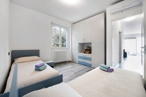 Una habitación de hotel moderna con dos camas, una ventana, un radiador y un armario.