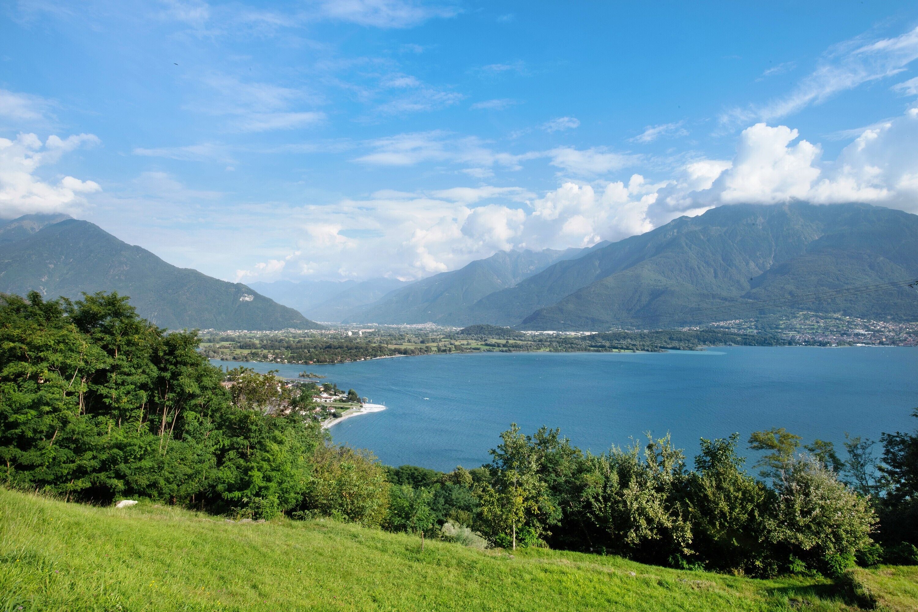 A coastal landscape with mountains, a lake, and a view of a town.