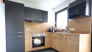 Eine moderne Küche mit dunklen Schränken, einem eingebauten Backofen und einer Holzausziehtafel.