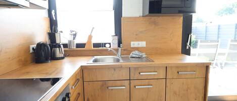 A modern kitchen with wooden cabinets, a stainless steel sink, and a black microwave.